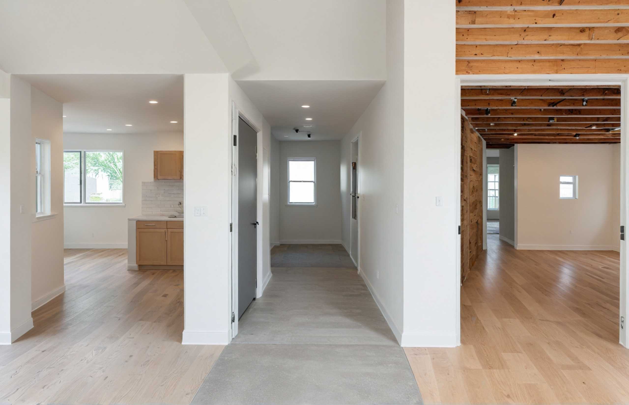 A hallway featuring polished wood floors and bright white walls, creating a clean and inviting atmosphere.